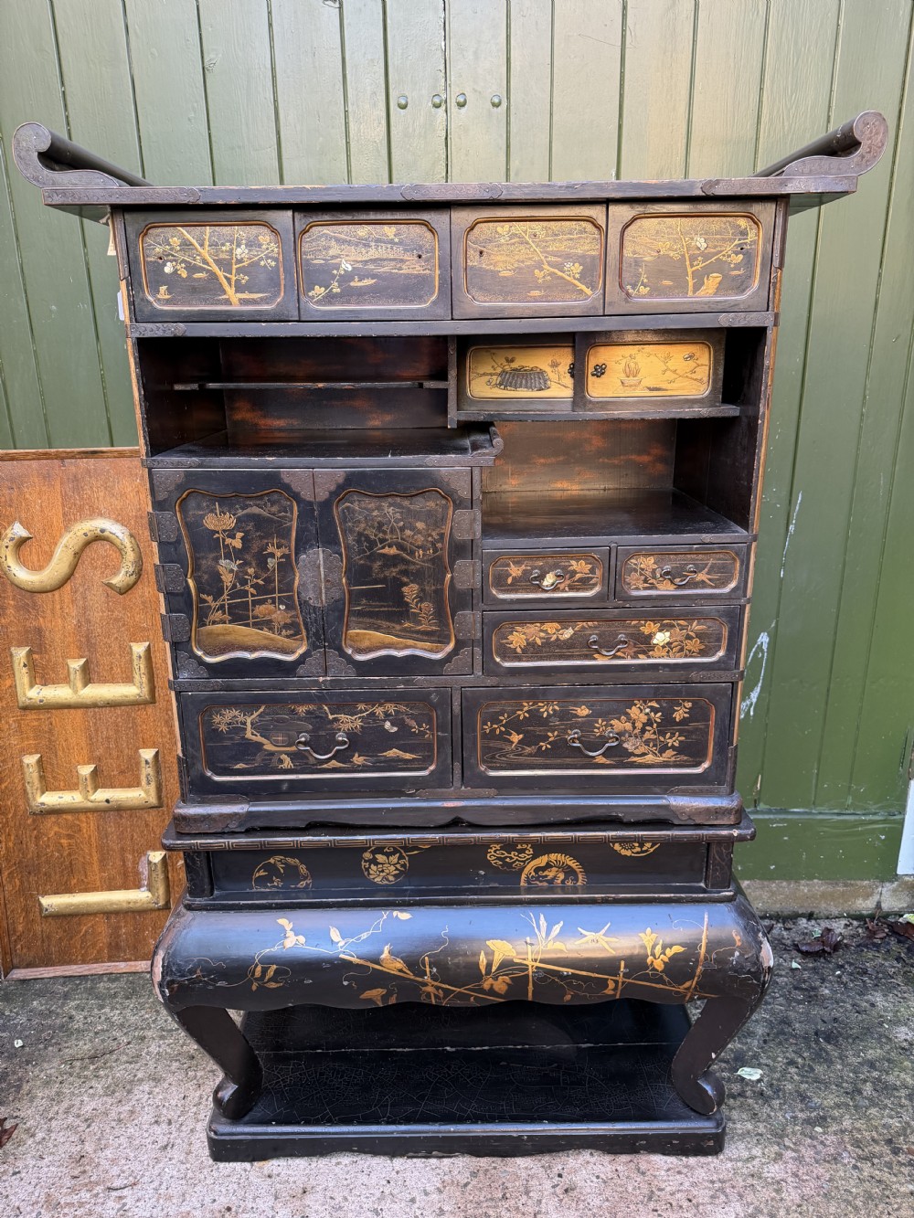 Late nineteenth-century Japanese Meiji period black lacquer shodana cabinet-on-stand with gold maki-e pictorial panels, asymmetrical shelves, and engraved metal fitments. View II