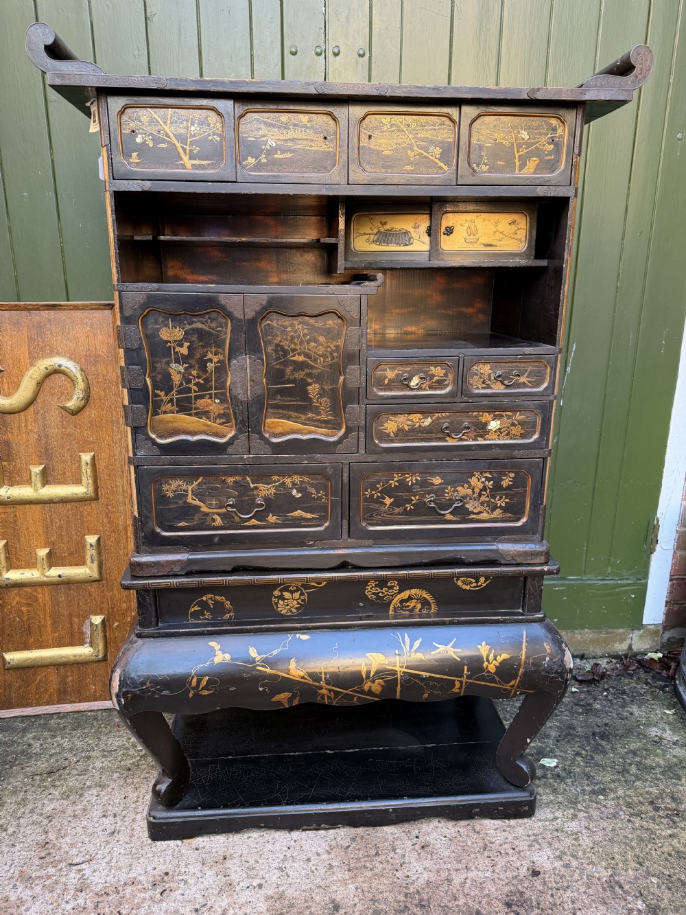 Late nineteenth-century Japanese Meiji period black lacquer shodana cabinet-on-stand with gold maki-e pictorial panels, asymmetrical shelves, and engraved metal fitments. View X