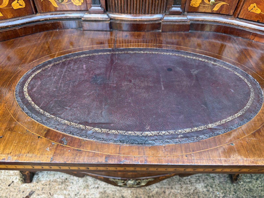 An antique Dutch walnut bureau with floral marquetry inlays, a curved cylinder front, three drawers, and decorative brass handles. View XIV