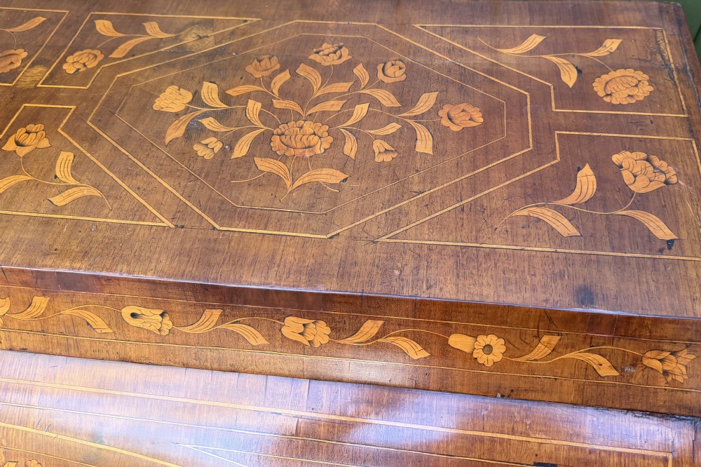 An antique Dutch walnut bureau with floral marquetry inlays, a curved cylinder front, three drawers, and decorative brass handles. View XXV