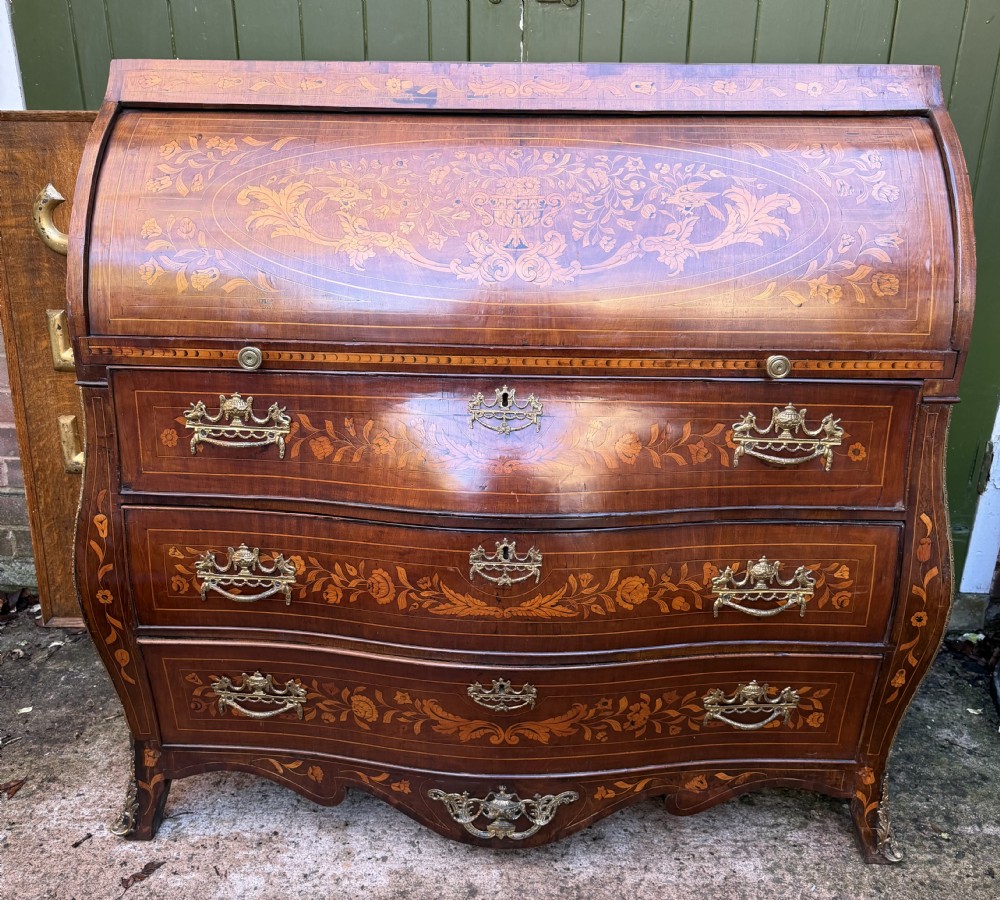 An antique Dutch walnut bureau with floral marquetry inlays, a curved cylinder front, three drawers, and decorative brass handles. View XXIX