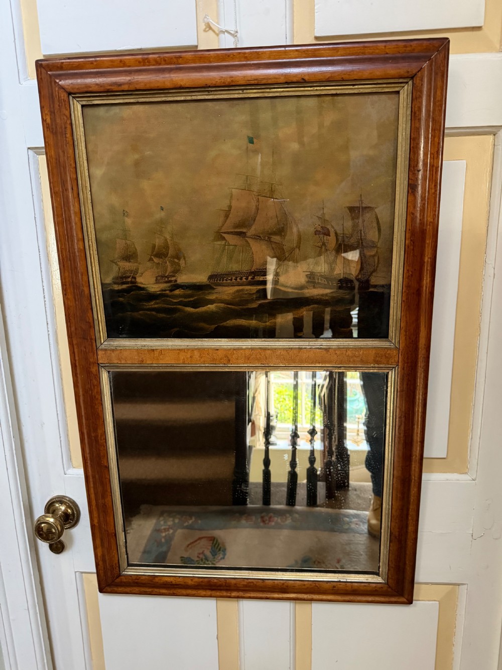 An early nineteenth-century rectangular maple-framed divided mirror featuring a reverse glass print of a naval engagement in the upper section and a reflective mirror below. View VII