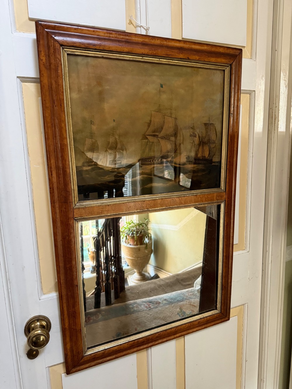 An early nineteenth-century rectangular maple-framed divided mirror featuring a reverse glass print of a naval engagement in the upper section and a reflective mirror below. View X