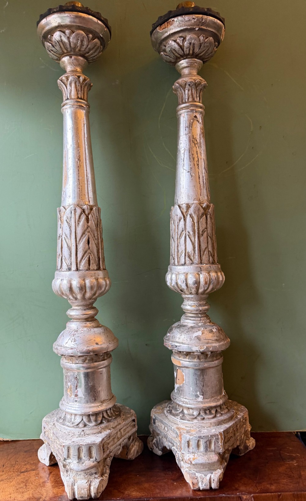 Pair of tall, hand-carved wooden altar candlesticks with an aged silver leaf finish, leaf motifs, and architectural bases. View V