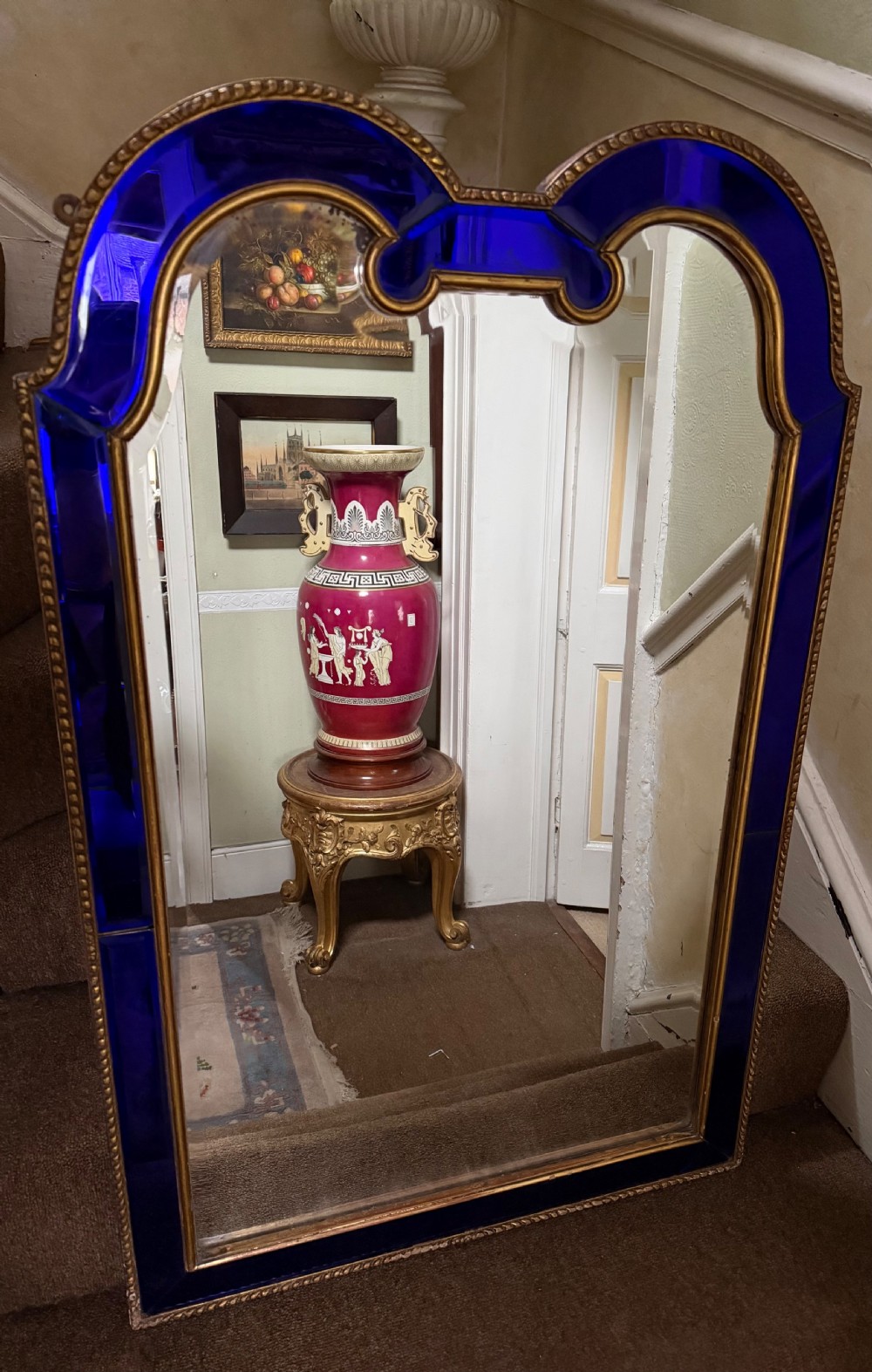 A late 19th-century wall mirror featuring a shaped arched top, cobalt blue glass margin borders, and an ornate gilded inner and outer moulding.