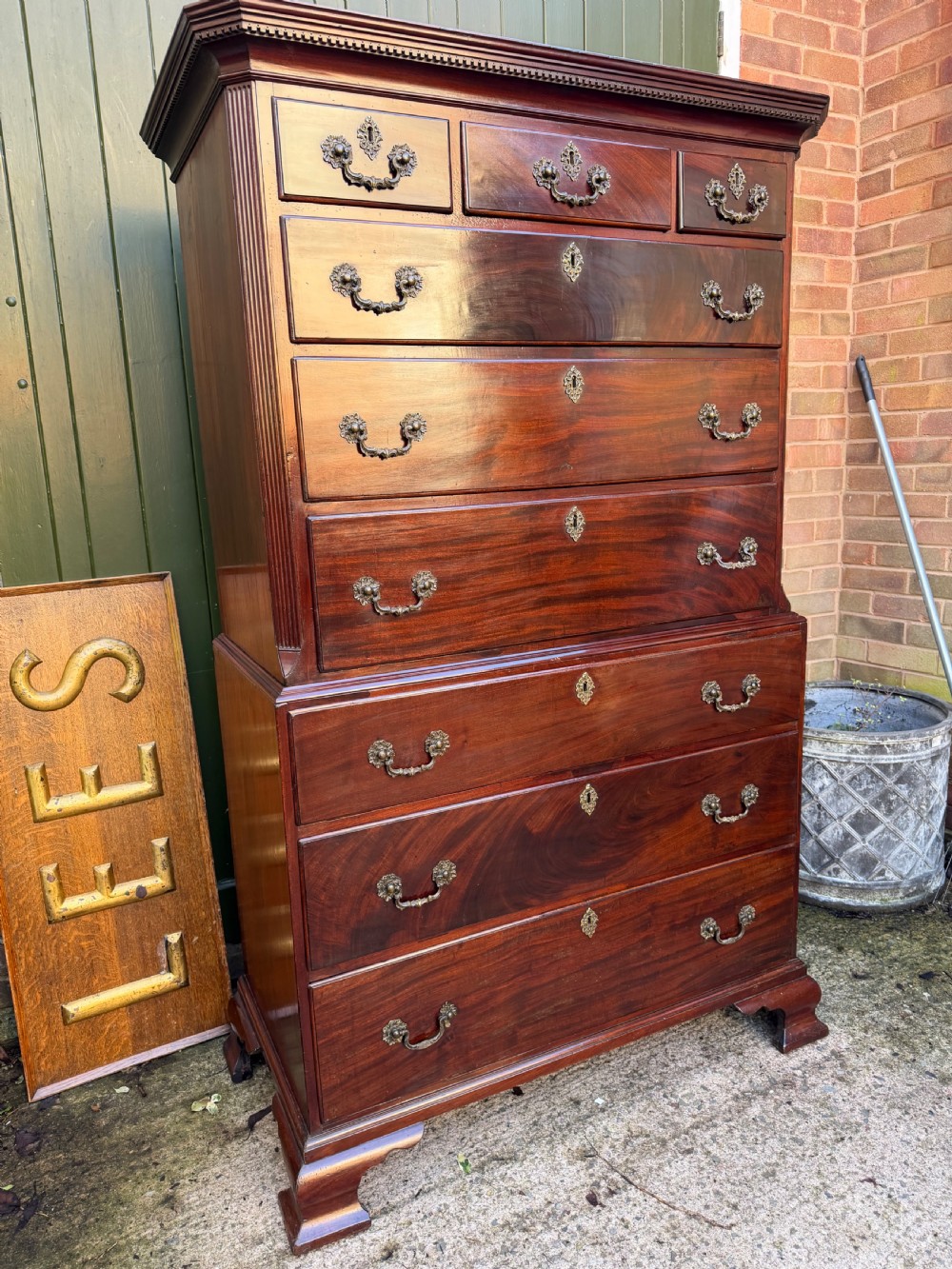 A mid-18th century George II red walnut chest-on-chest featuring a dentil moulded cornice, brass swan-neck handles, and bracket feet. View V