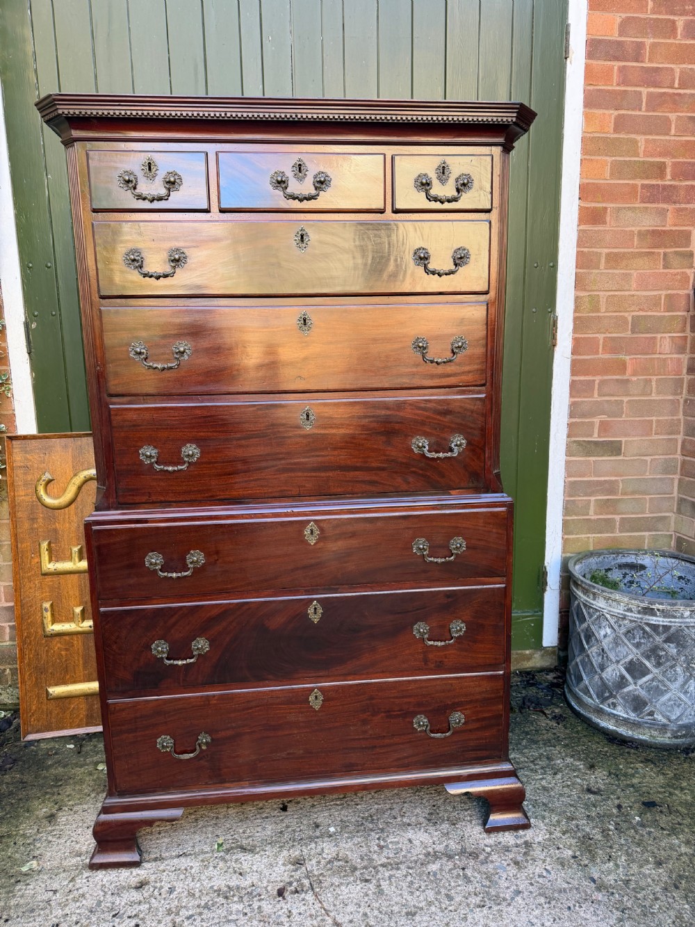 A mid-18th century George II red walnut chest-on-chest featuring a dentil moulded cornice, brass swan-neck handles, and bracket feet. View VI