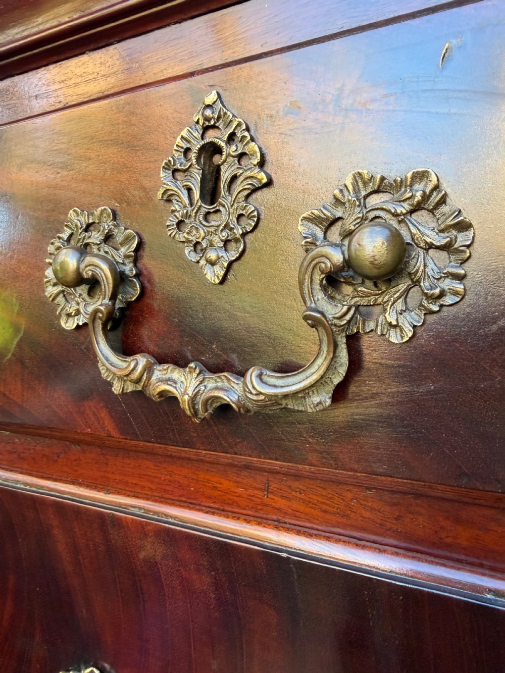 A mid-18th century George II red walnut chest-on-chest featuring a dentil moulded cornice, brass swan-neck handles, and bracket feet. View VII
