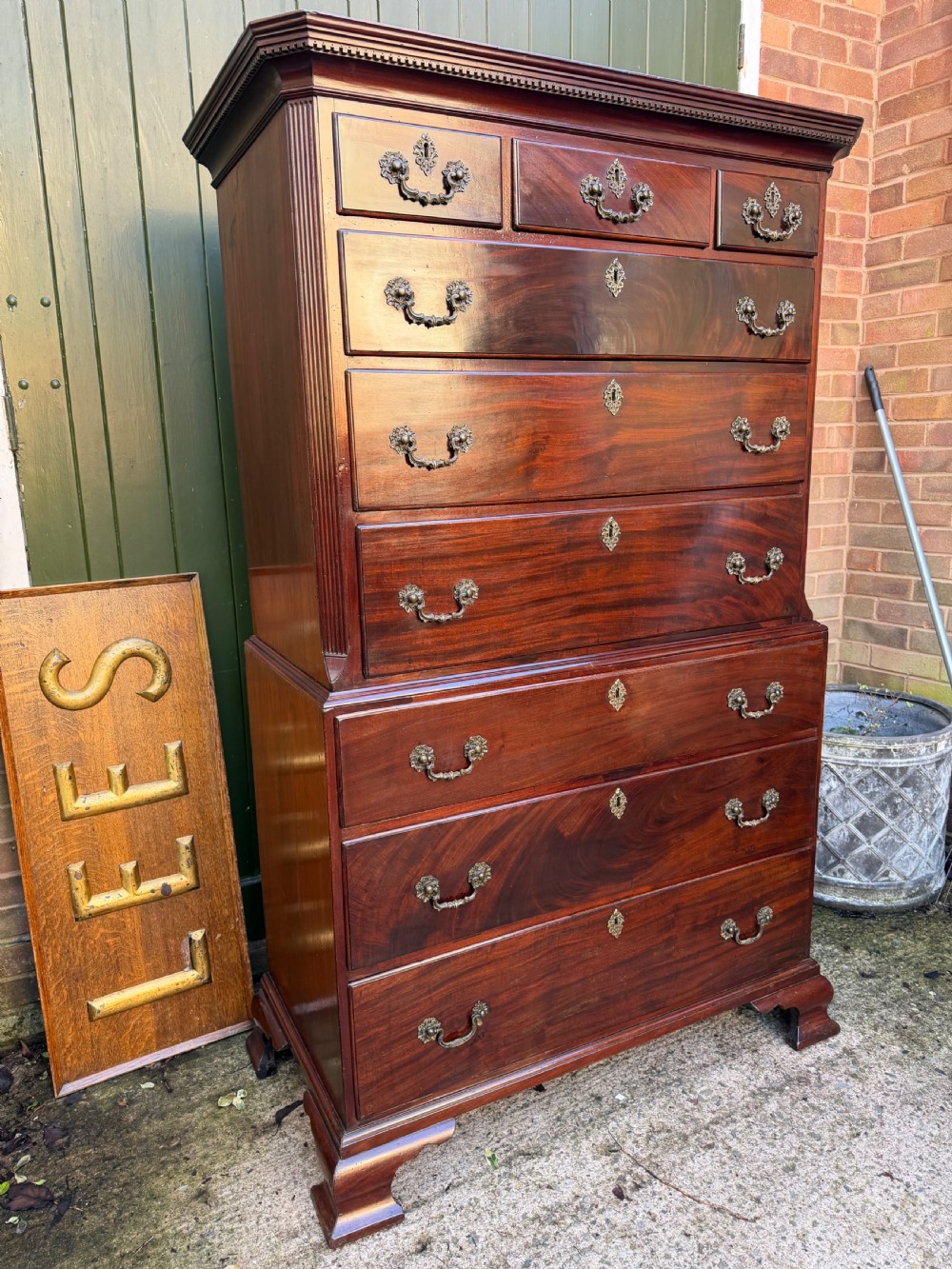 A mid-18th century George II red walnut chest-on-chest featuring a dentil moulded cornice, brass swan-neck handles, and bracket feet. View VIII