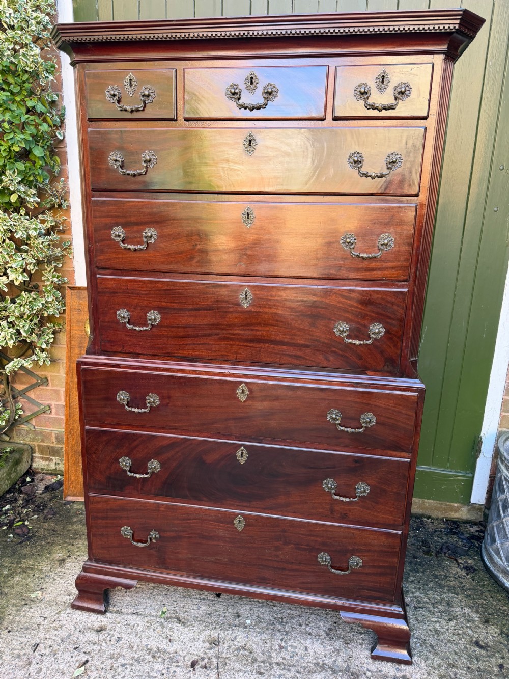 A mid-18th century George II red walnut chest-on-chest featuring a dentil moulded cornice, brass swan-neck handles, and bracket feet. View X