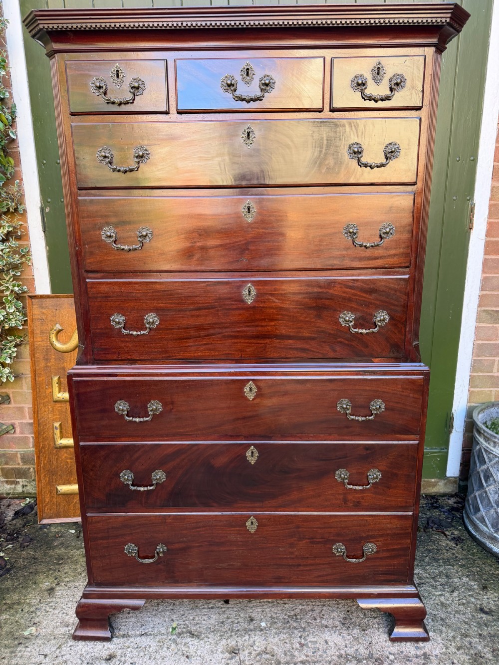 A mid-18th century George II red walnut chest-on-chest featuring a dentil moulded cornice, brass swan-neck handles, and bracket feet. View XII