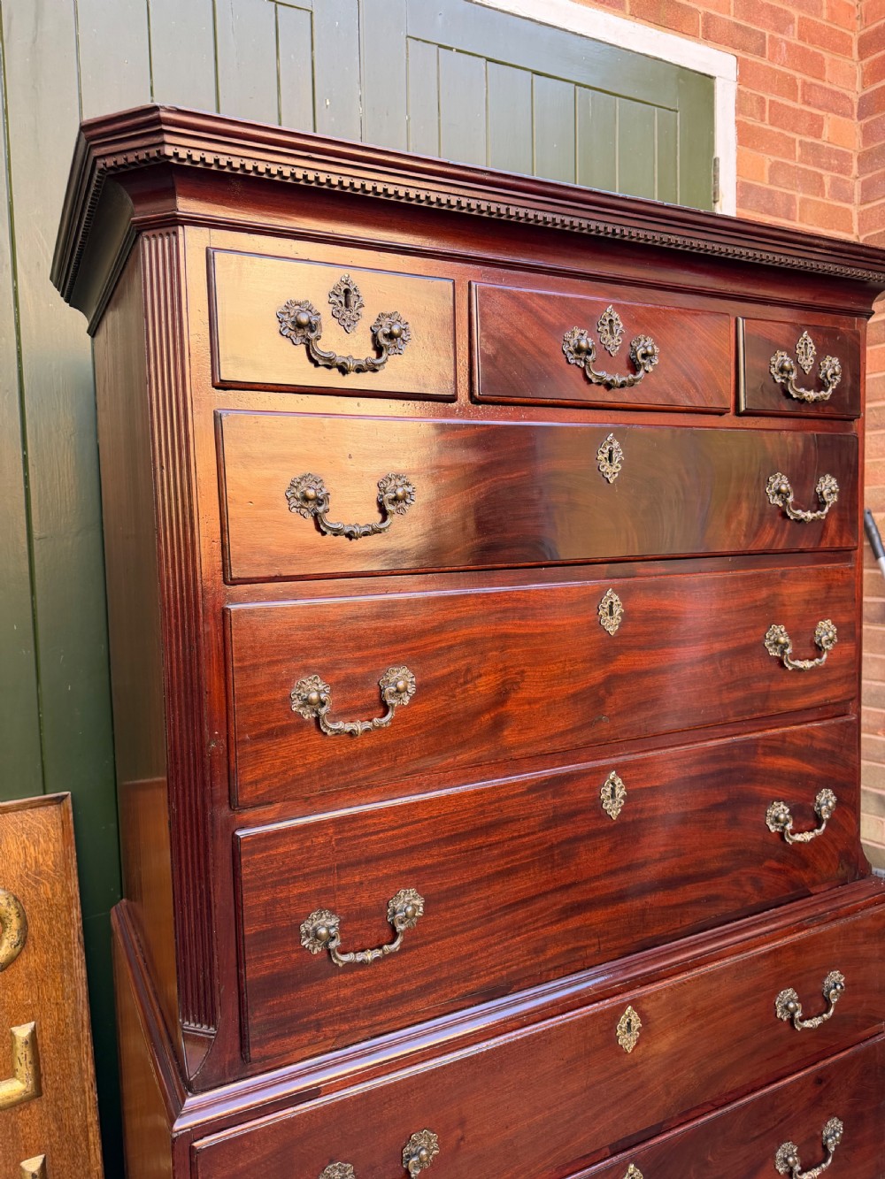 A mid-18th century George II red walnut chest-on-chest featuring a dentil moulded cornice, brass swan-neck handles, and bracket feet. View XIII