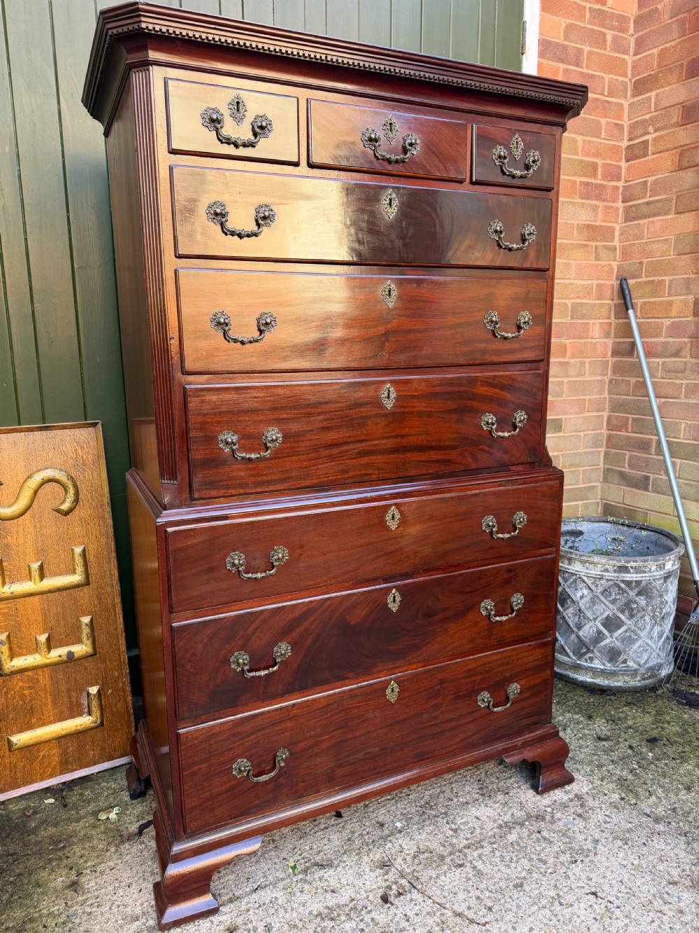 A mid-18th century George II red walnut chest-on-chest featuring a dentil moulded cornice, brass swan-neck handles, and bracket feet. View XIV