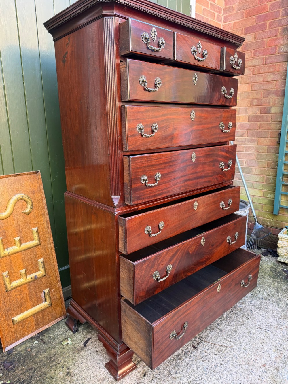 A mid-18th century George II red walnut chest-on-chest featuring a dentil moulded cornice, brass swan-neck handles, and bracket feet. View XVII