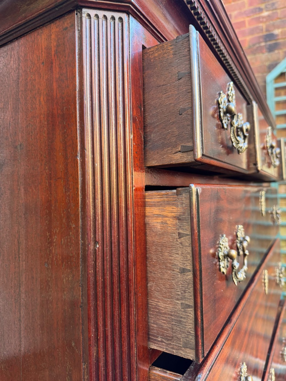 A mid-18th century George II red walnut chest-on-chest featuring a dentil moulded cornice, brass swan-neck handles, and bracket feet. View XVIII