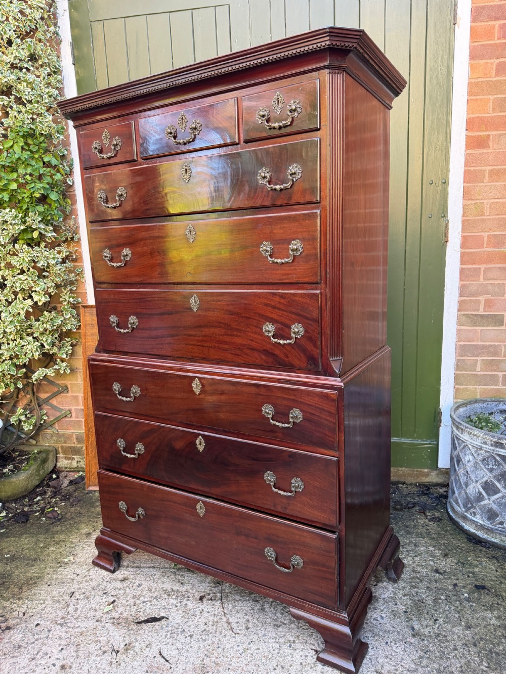 A mid-18th century George II red walnut chest-on-chest featuring a dentil moulded cornice, brass swan-neck handles, and bracket feet. View XIX