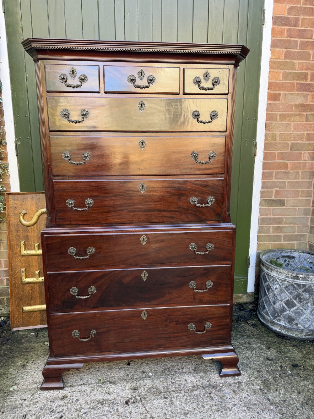 A mid-18th century George II red walnut chest-on-chest featuring a dentil moulded cornice, brass swan-neck handles, and bracket feet. View XXI