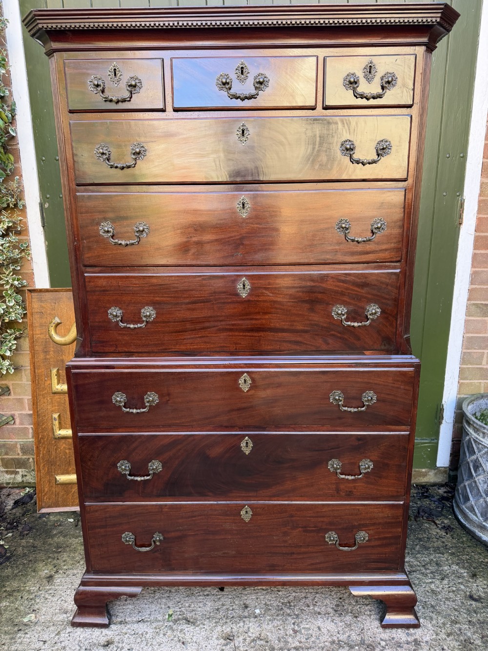 A mid-18th century George II red walnut chest-on-chest featuring a dentil moulded cornice, brass swan-neck handles, and bracket feet. View XXIV