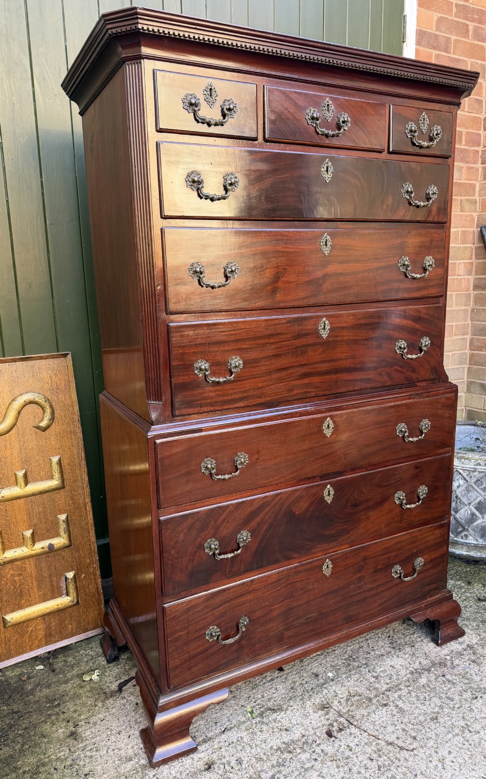 A mid-18th century George II red walnut chest-on-chest featuring a dentil moulded cornice, brass swan-neck handles, and bracket feet. View XXV