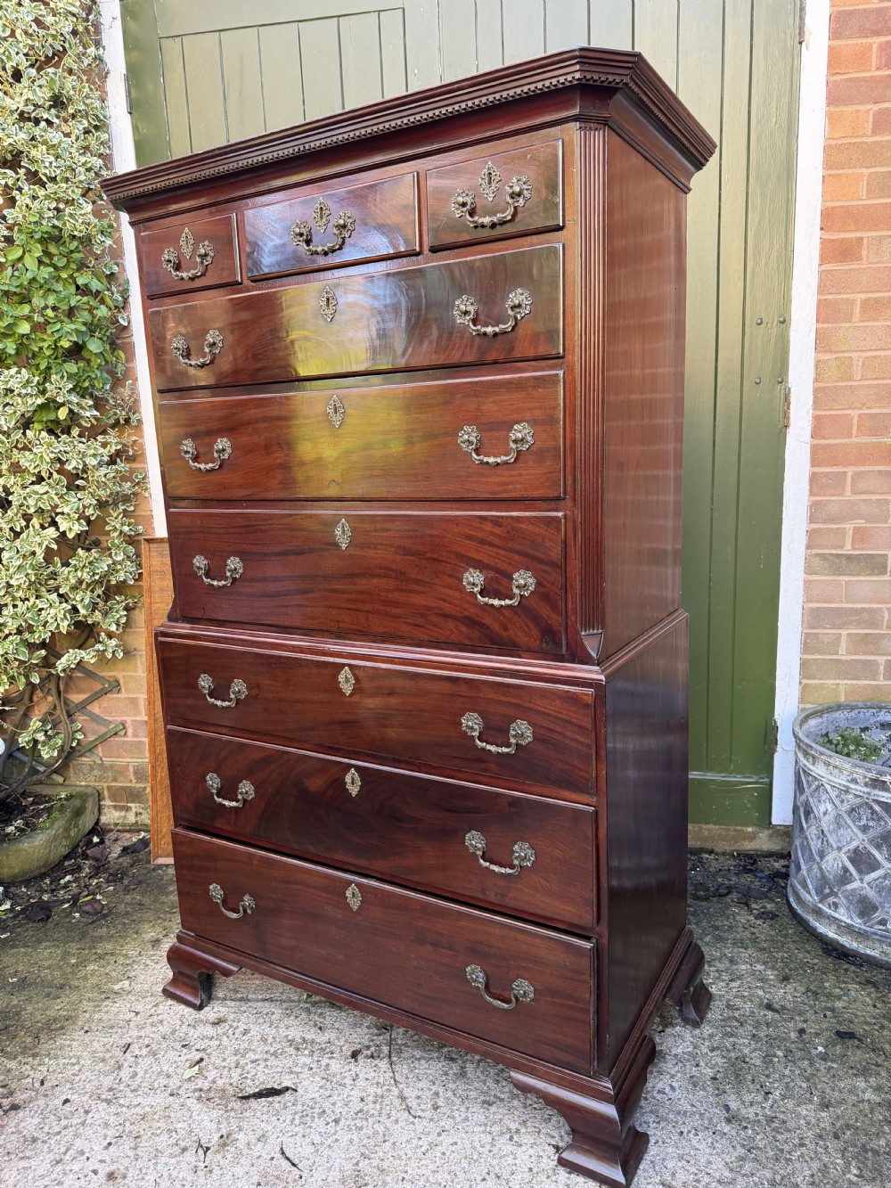 A mid-18th century George II red walnut chest-on-chest featuring a dentil moulded cornice, brass swan-neck handles, and bracket feet. View XXVI