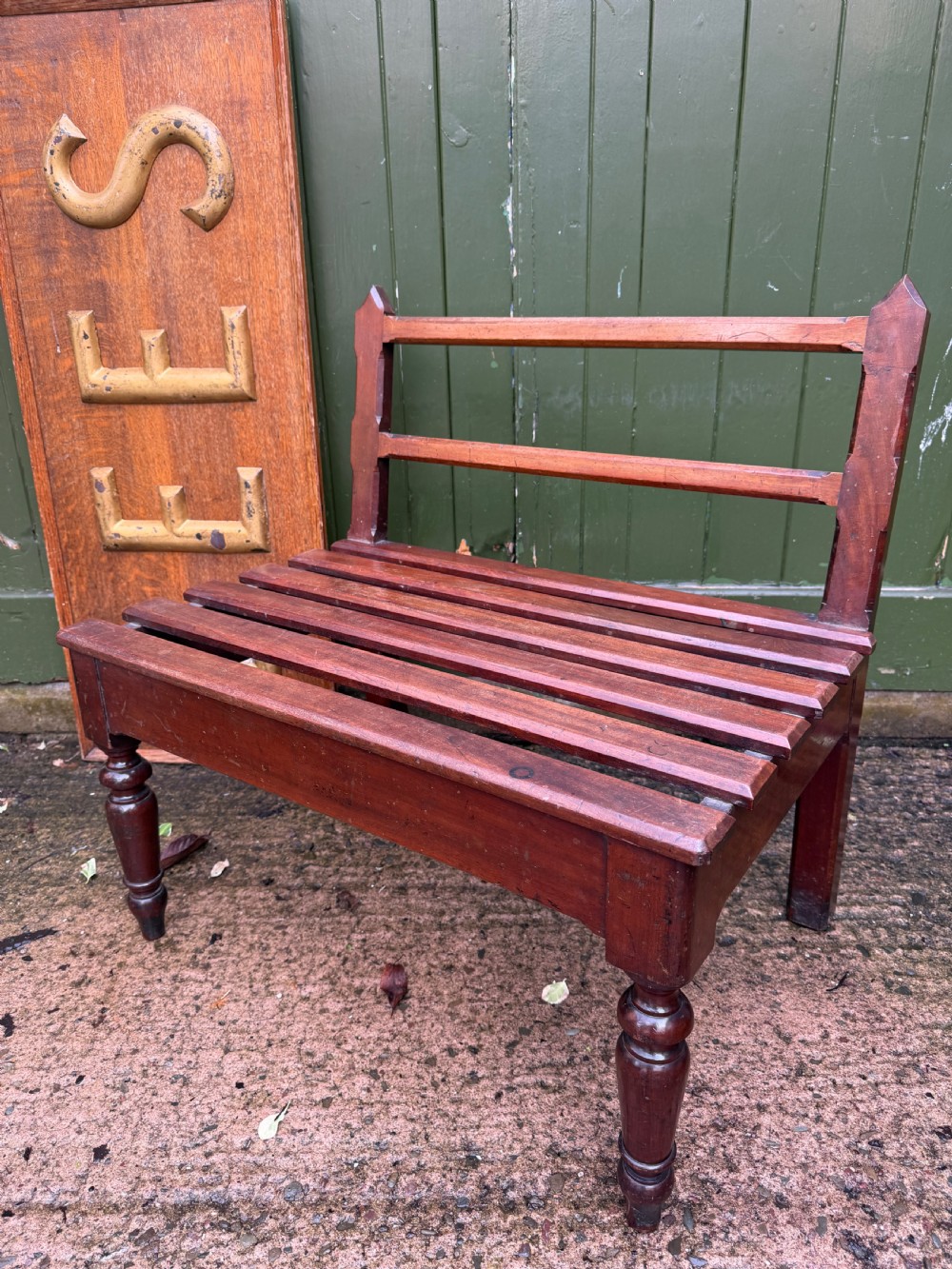 A mid-19th century mahogany luggage stand with a slatted platform, turned front legs, and a raised raked rear upstand.