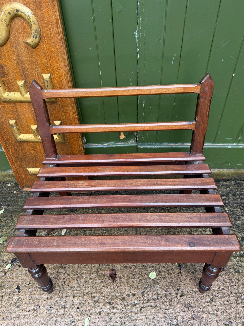 A mid-19th century mahogany luggage stand with a slatted platform, turned front legs, and a raised raked rear upstand. View II
