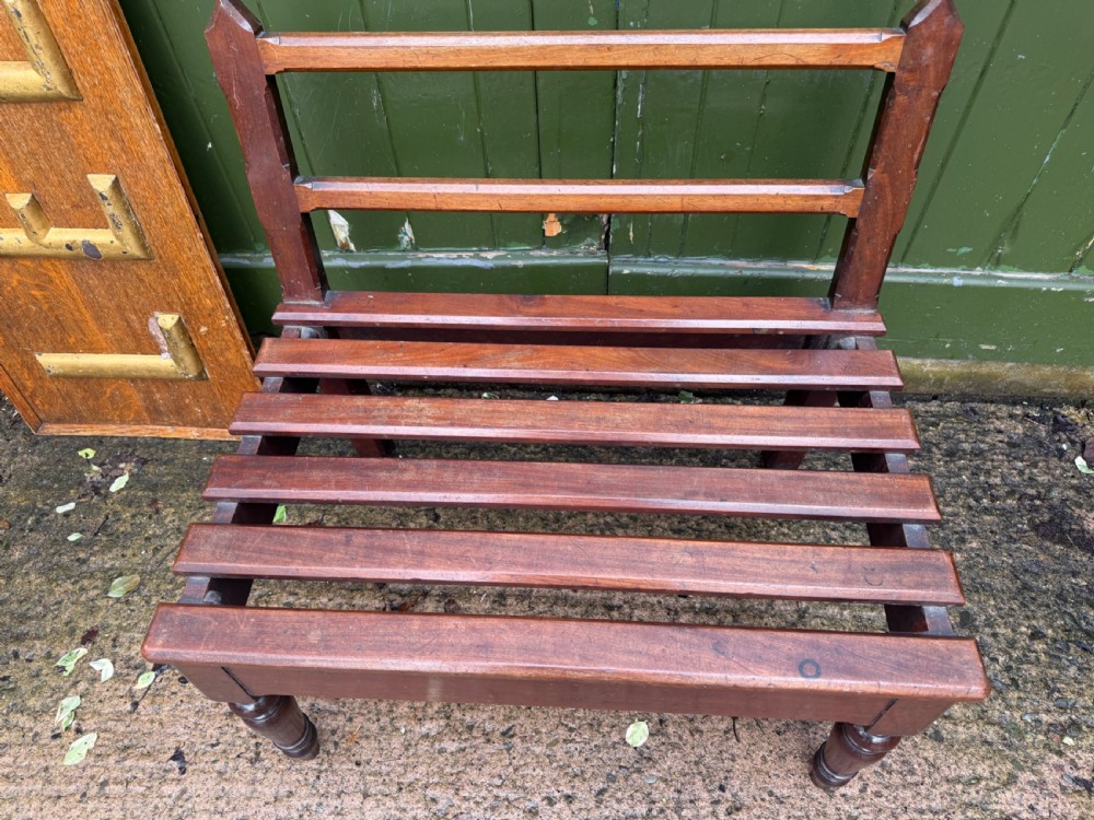 A mid-19th century mahogany luggage stand with a slatted platform, turned front legs, and a raised raked rear upstand. View XVI