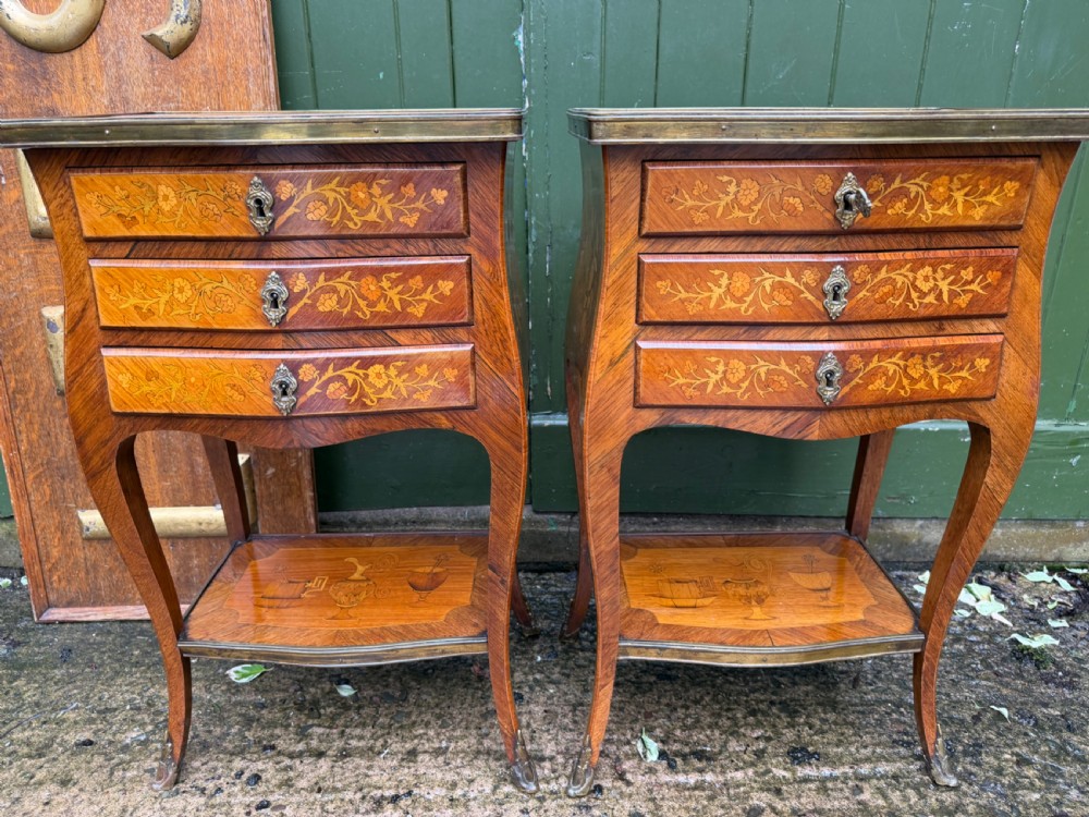 A pair of French marquetry bedside tables featuring three drawers with floral inlays, brass mounts, curved legs, and a lower tier shelf. View III