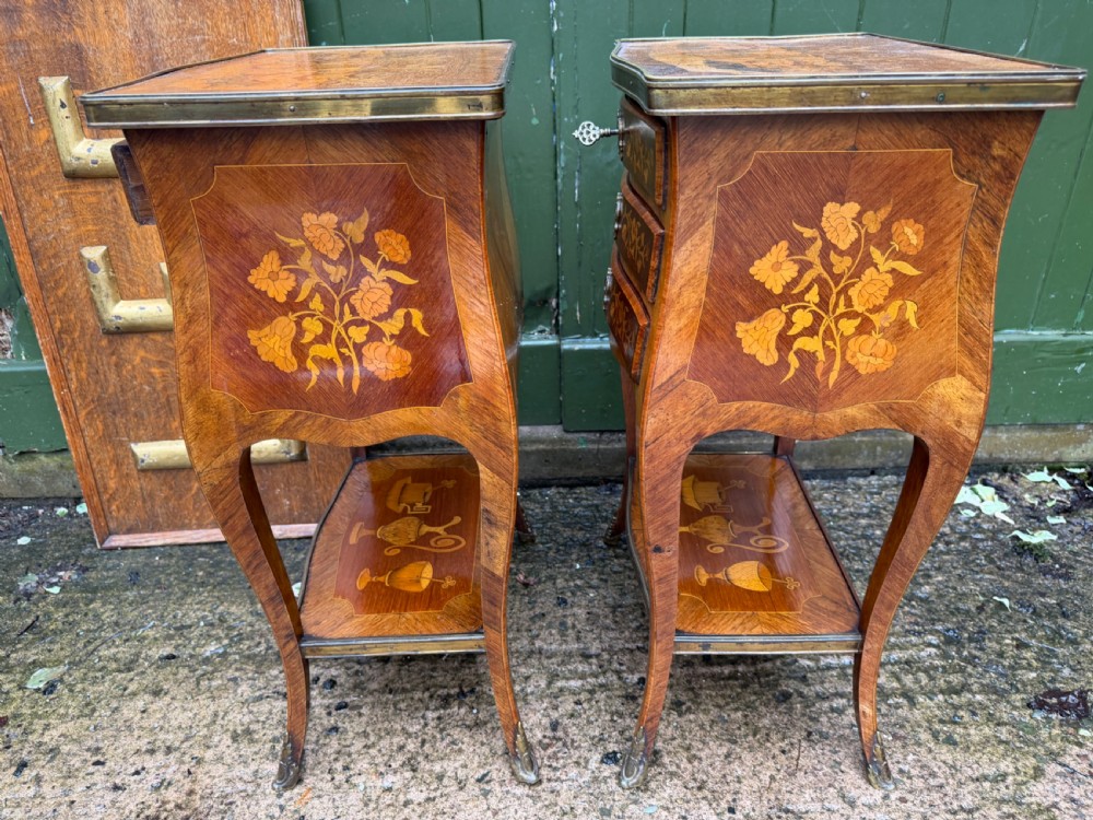 A pair of French marquetry bedside tables featuring three drawers with floral inlays, brass mounts, curved legs, and a lower tier shelf. View XI