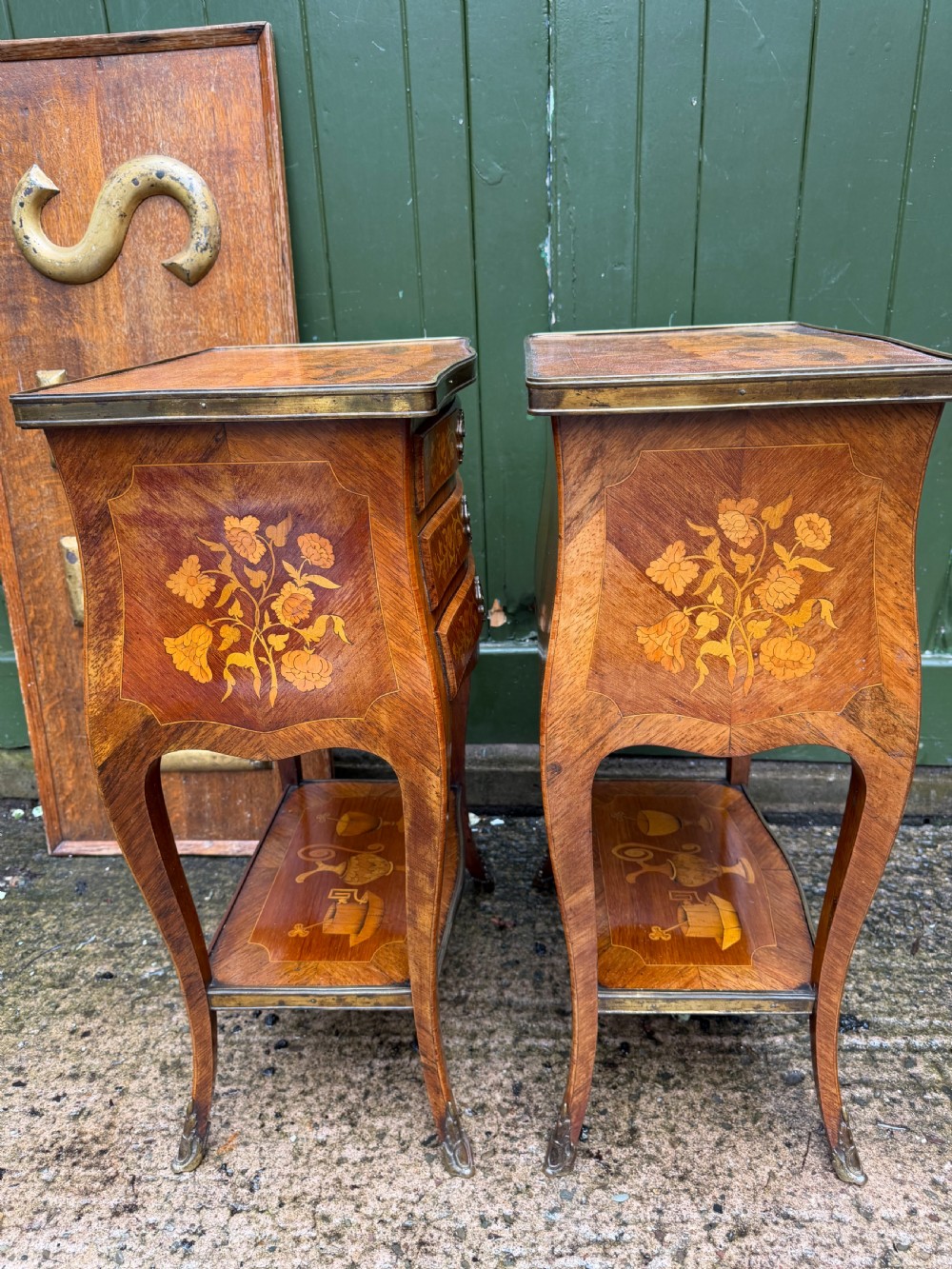 A pair of French marquetry bedside tables featuring three drawers with floral inlays, brass mounts, curved legs, and a lower tier shelf. View XIV
