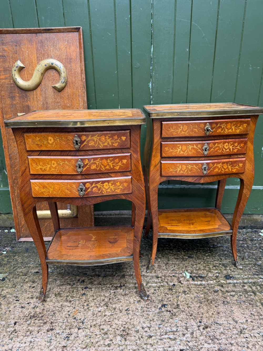 A pair of French marquetry bedside tables featuring three drawers with floral inlays, brass mounts, curved legs, and a lower tier shelf. View XVIII