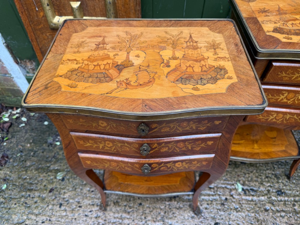 A pair of French marquetry bedside tables featuring three drawers with floral inlays, brass mounts, curved legs, and a lower tier shelf. View XIX