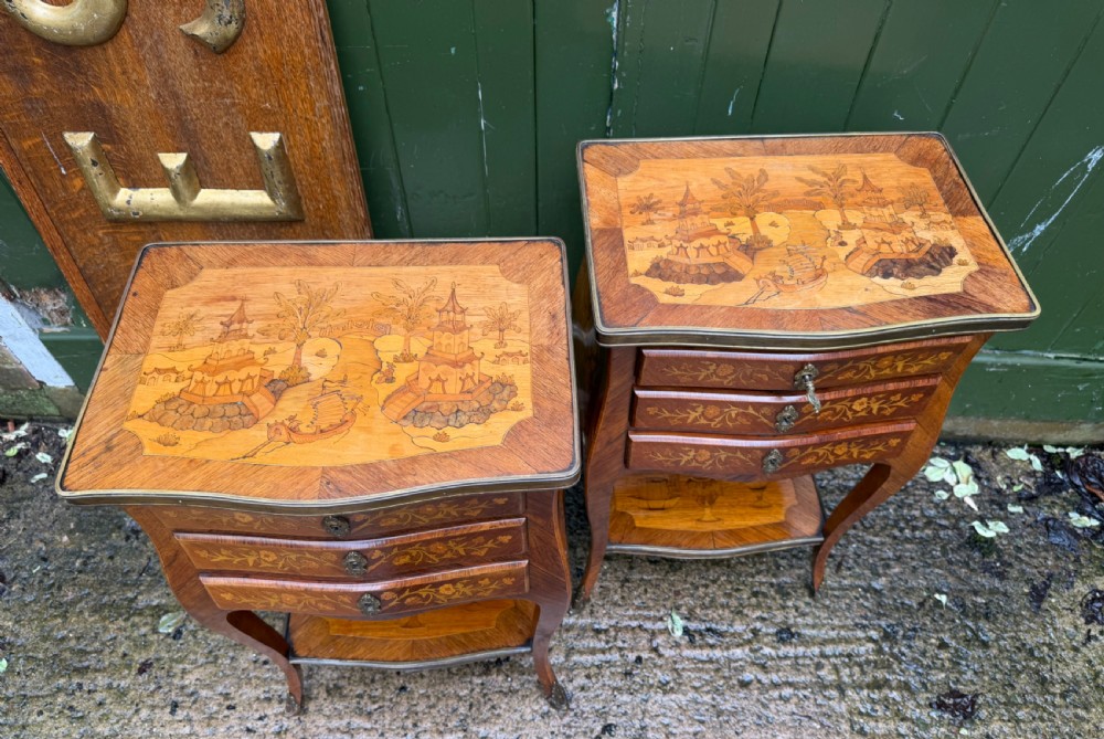 A pair of French marquetry bedside tables featuring three drawers with floral inlays, brass mounts, curved legs, and a lower tier shelf. View XXII