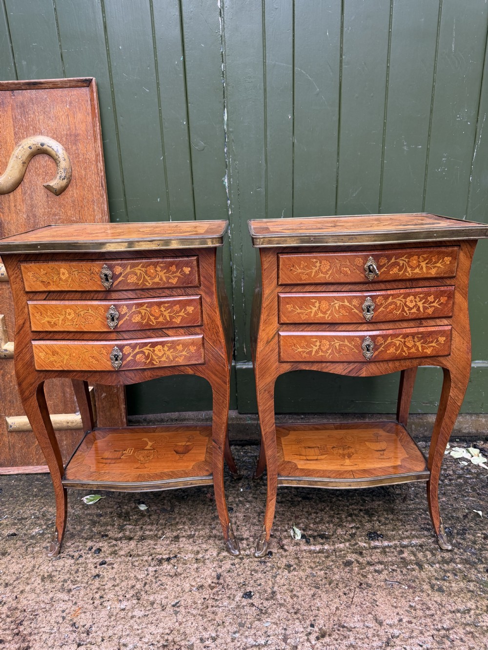 A pair of French marquetry bedside tables featuring three drawers with floral inlays, brass mounts, curved legs, and a lower tier shelf. View XXIII