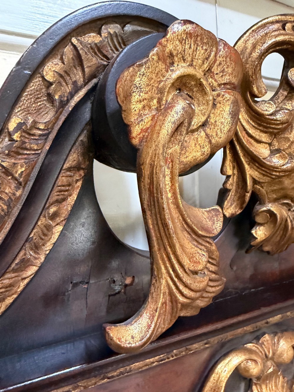 A George II style walnut wall mirror featuring a carved parcel gilt frame with a swan-neck pediment and central cartouche cresting. View IV