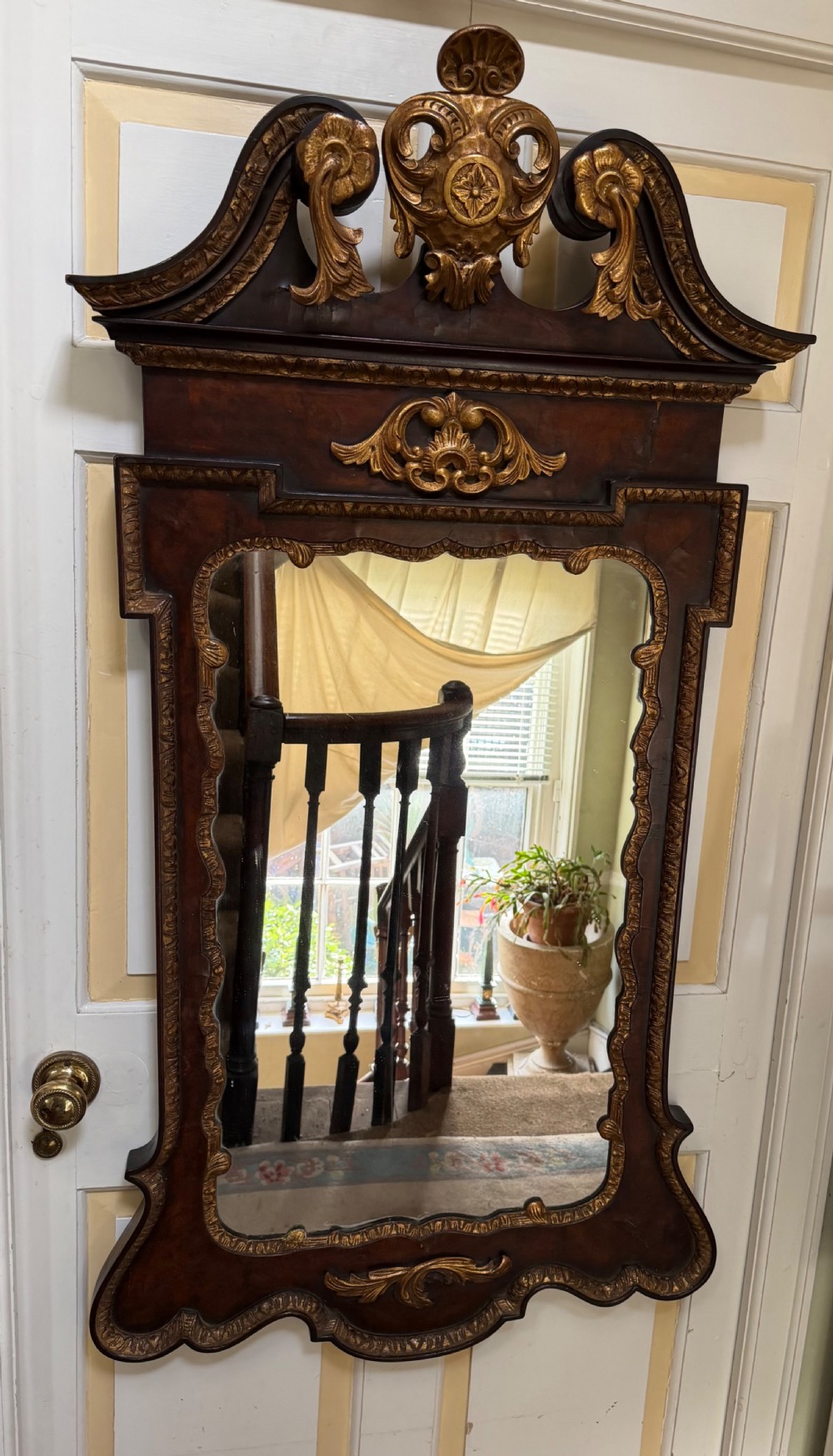 A George II style walnut wall mirror featuring a carved parcel gilt frame with a swan-neck pediment and central cartouche cresting. View VI