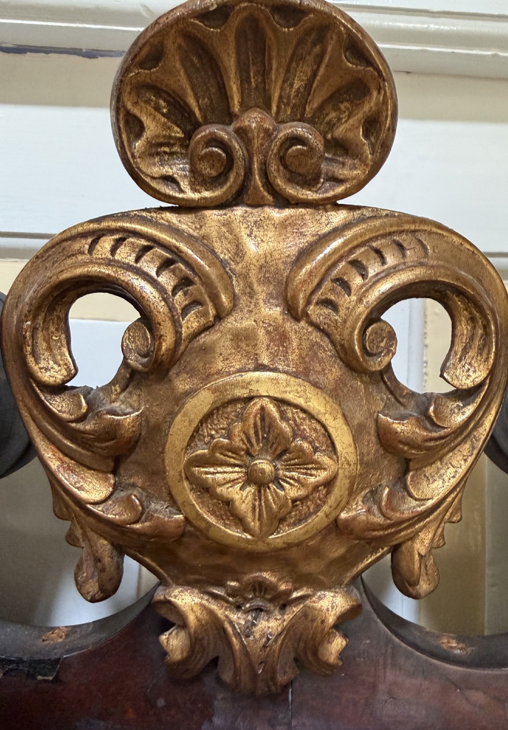A George II style walnut wall mirror featuring a carved parcel gilt frame with a swan-neck pediment and central cartouche cresting. View VII