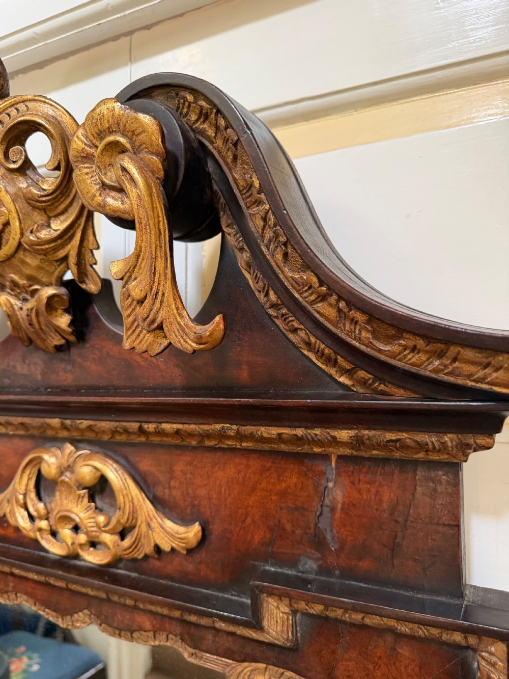 A George II style walnut wall mirror featuring a carved parcel gilt frame with a swan-neck pediment and central cartouche cresting. View VIII