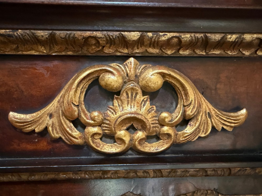 A George II style walnut wall mirror featuring a carved parcel gilt frame with a swan-neck pediment and central cartouche cresting. View IX