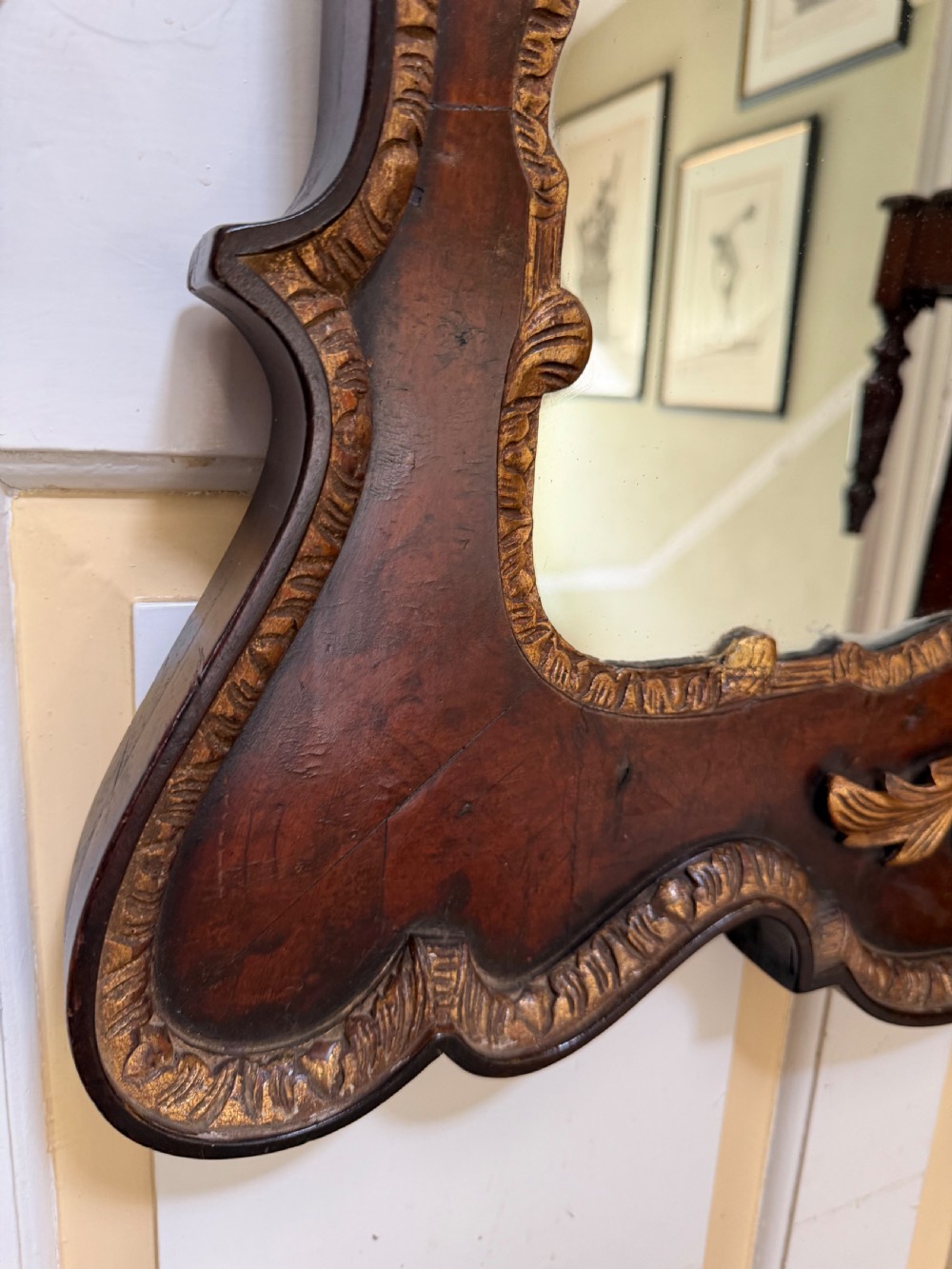 A George II style walnut wall mirror featuring a carved parcel gilt frame with a swan-neck pediment and central cartouche cresting. View X