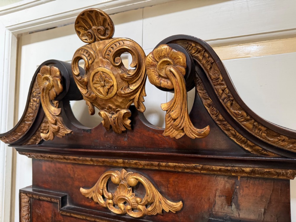 A George II style walnut wall mirror featuring a carved parcel gilt frame with a swan-neck pediment and central cartouche cresting. View XIV