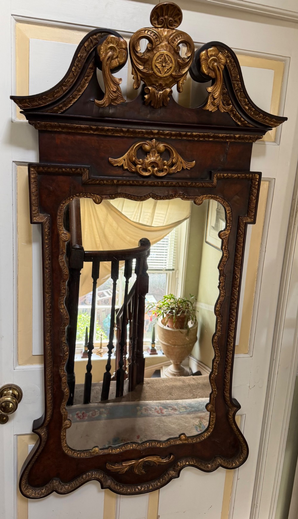 A George II style walnut wall mirror featuring a carved parcel gilt frame with a swan-neck pediment and central cartouche cresting. View XVI