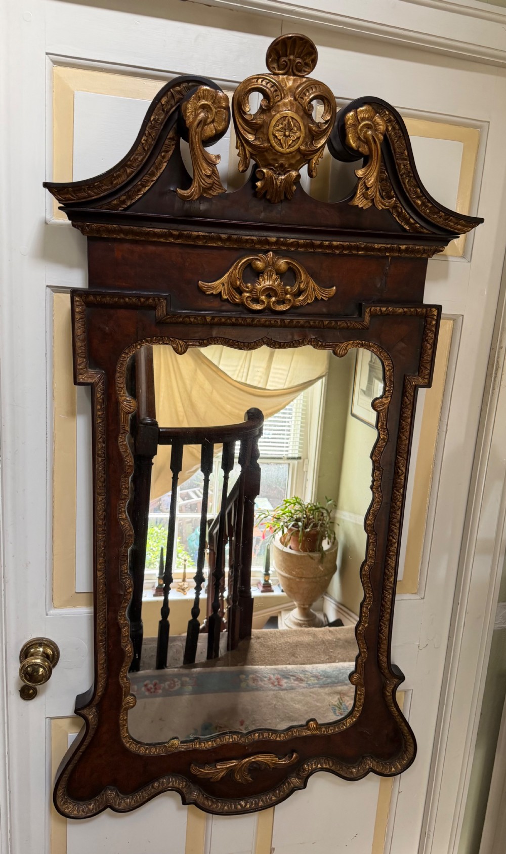 A George II style walnut wall mirror featuring a carved parcel gilt frame with a swan-neck pediment and central cartouche cresting. View XVII