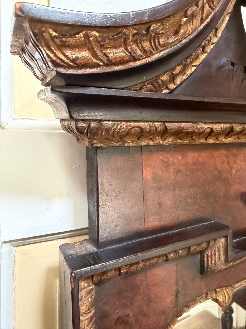 A George II style walnut wall mirror featuring a carved parcel gilt frame with a swan-neck pediment and central cartouche cresting. View XVIII