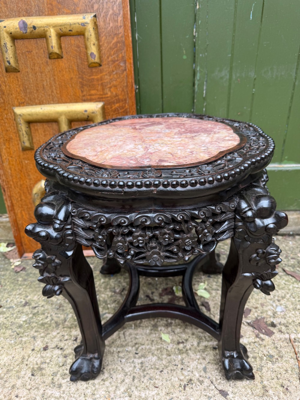 A late nineteenth-century Chinese carved dark hardwood jardiniere stand featuring a circular inset pink variegated marble top, intricate pierced floral aprons, and carved cabriole legs.