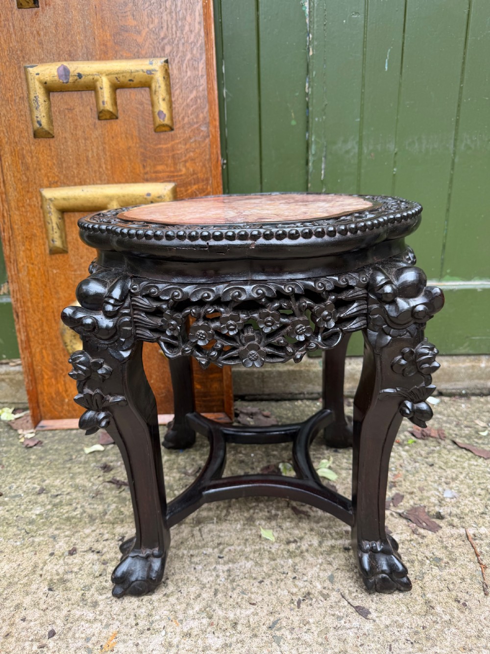 A late nineteenth-century Chinese carved dark hardwood jardiniere stand featuring a circular inset pink variegated marble top, intricate pierced floral aprons, and carved cabriole legs. View V