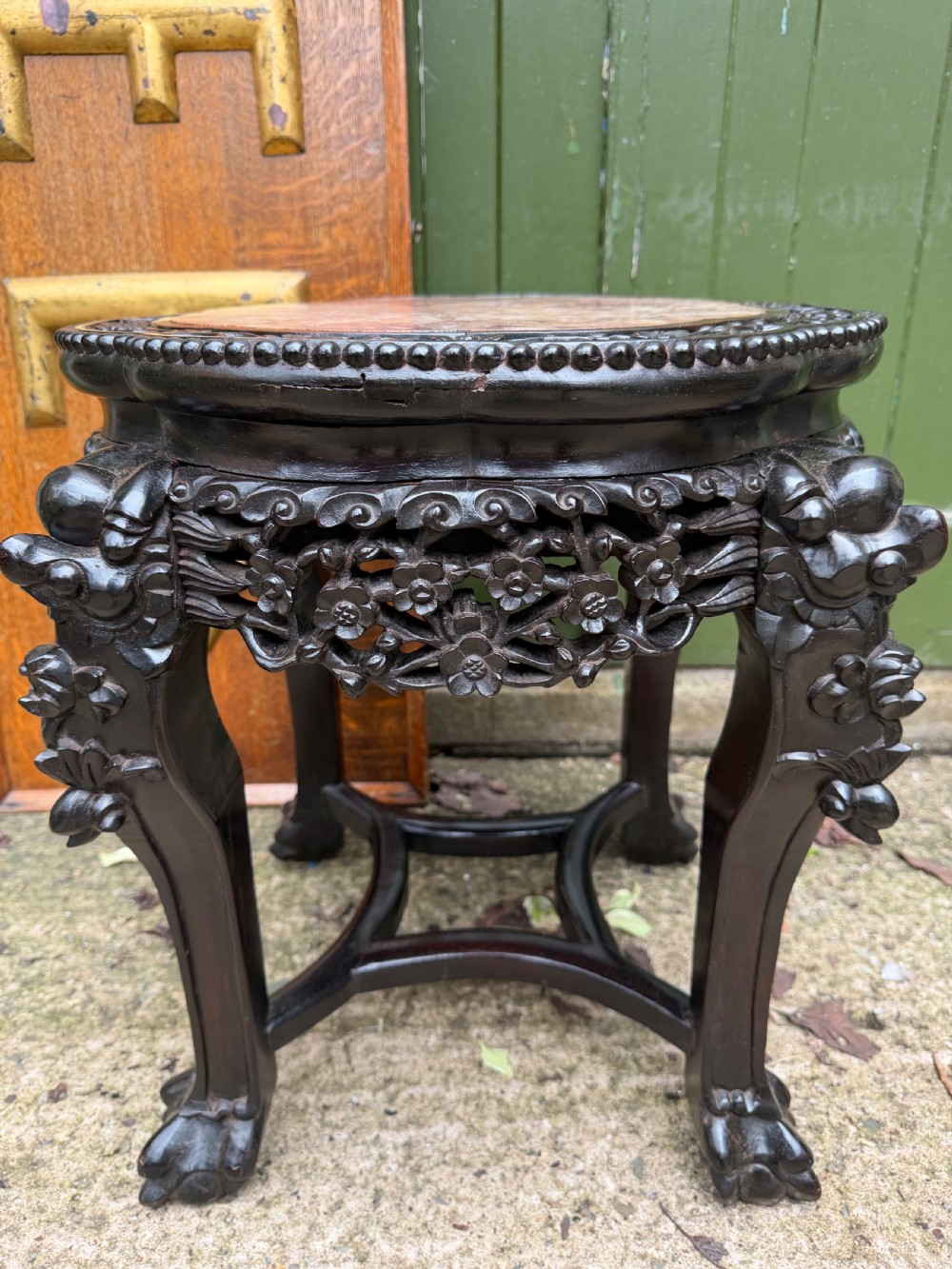 A late nineteenth-century Chinese carved dark hardwood jardiniere stand featuring a circular inset pink variegated marble top, intricate pierced floral aprons, and carved cabriole legs. View VI