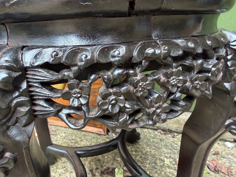 A late nineteenth-century Chinese carved dark hardwood jardiniere stand featuring a circular inset pink variegated marble top, intricate pierced floral aprons, and carved cabriole legs. View VII
