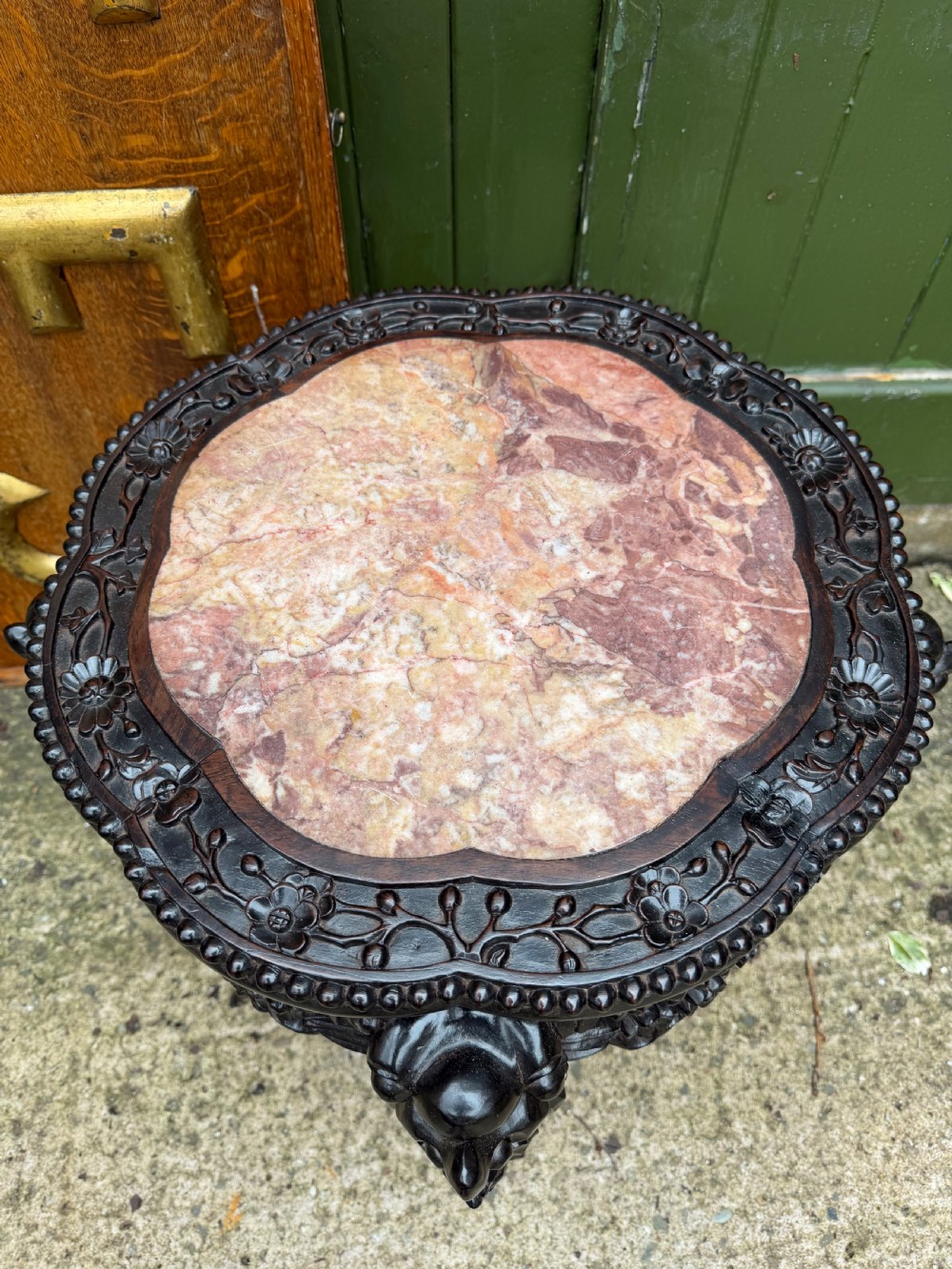 A late nineteenth-century Chinese carved dark hardwood jardiniere stand featuring a circular inset pink variegated marble top, intricate pierced floral aprons, and carved cabriole legs. View VIII