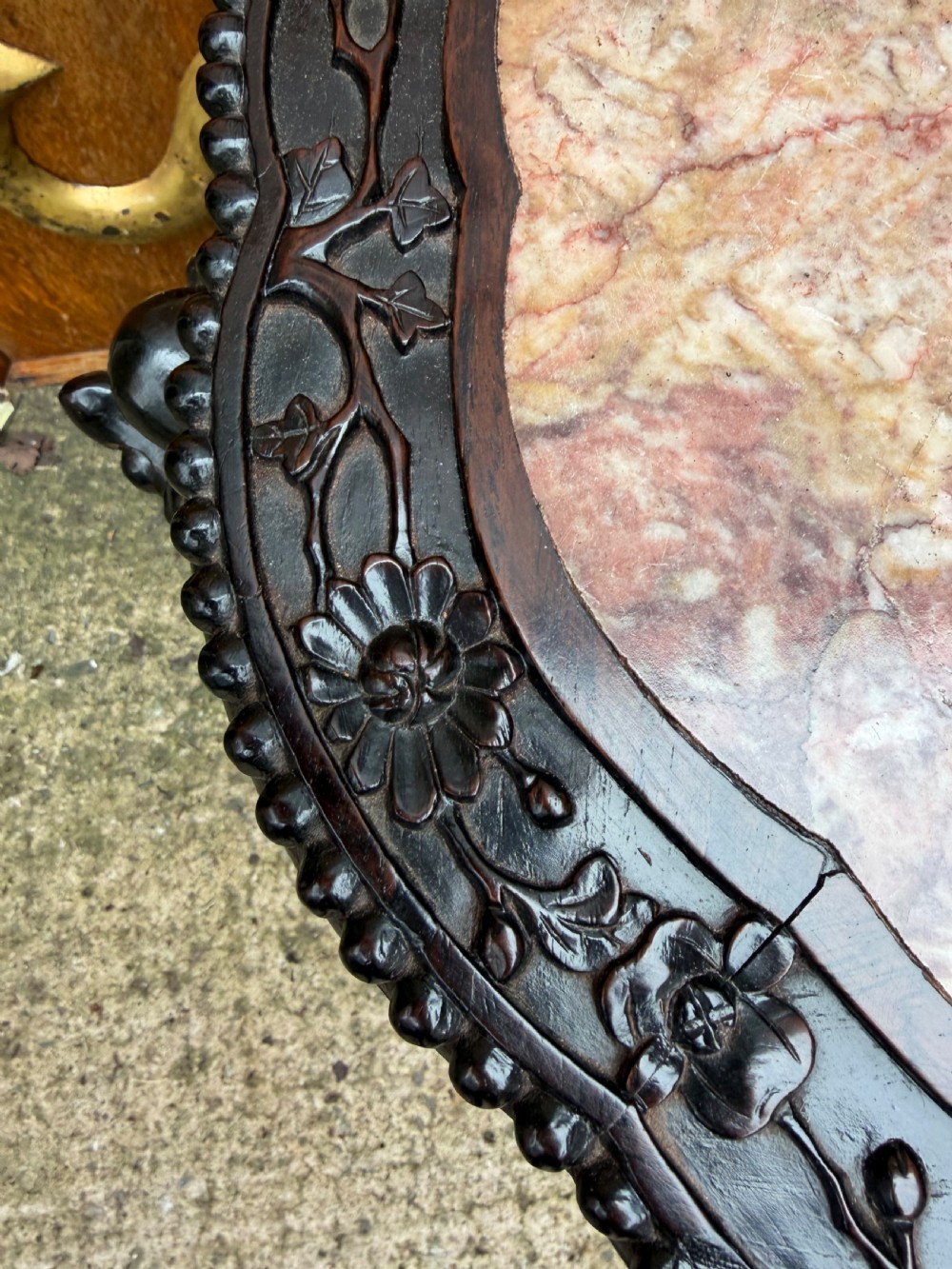 A late nineteenth-century Chinese carved dark hardwood jardiniere stand featuring a circular inset pink variegated marble top, intricate pierced floral aprons, and carved cabriole legs. View IX